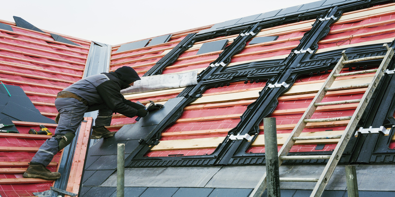 roofer fitting slate roof tiles onto building